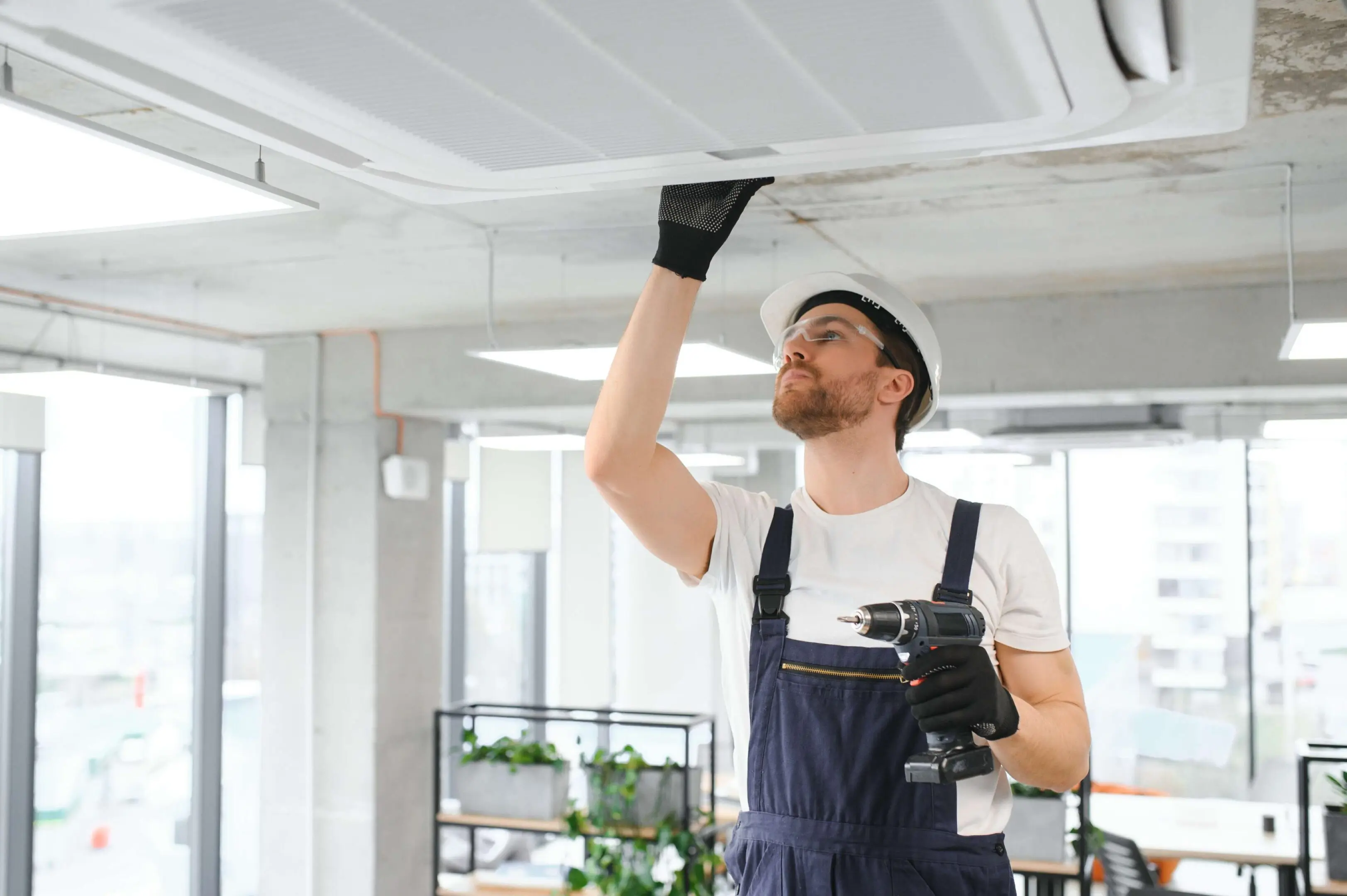 Wheeler's Heating & Air Conditioning Technician inspecting ceiling air conditioning unit.