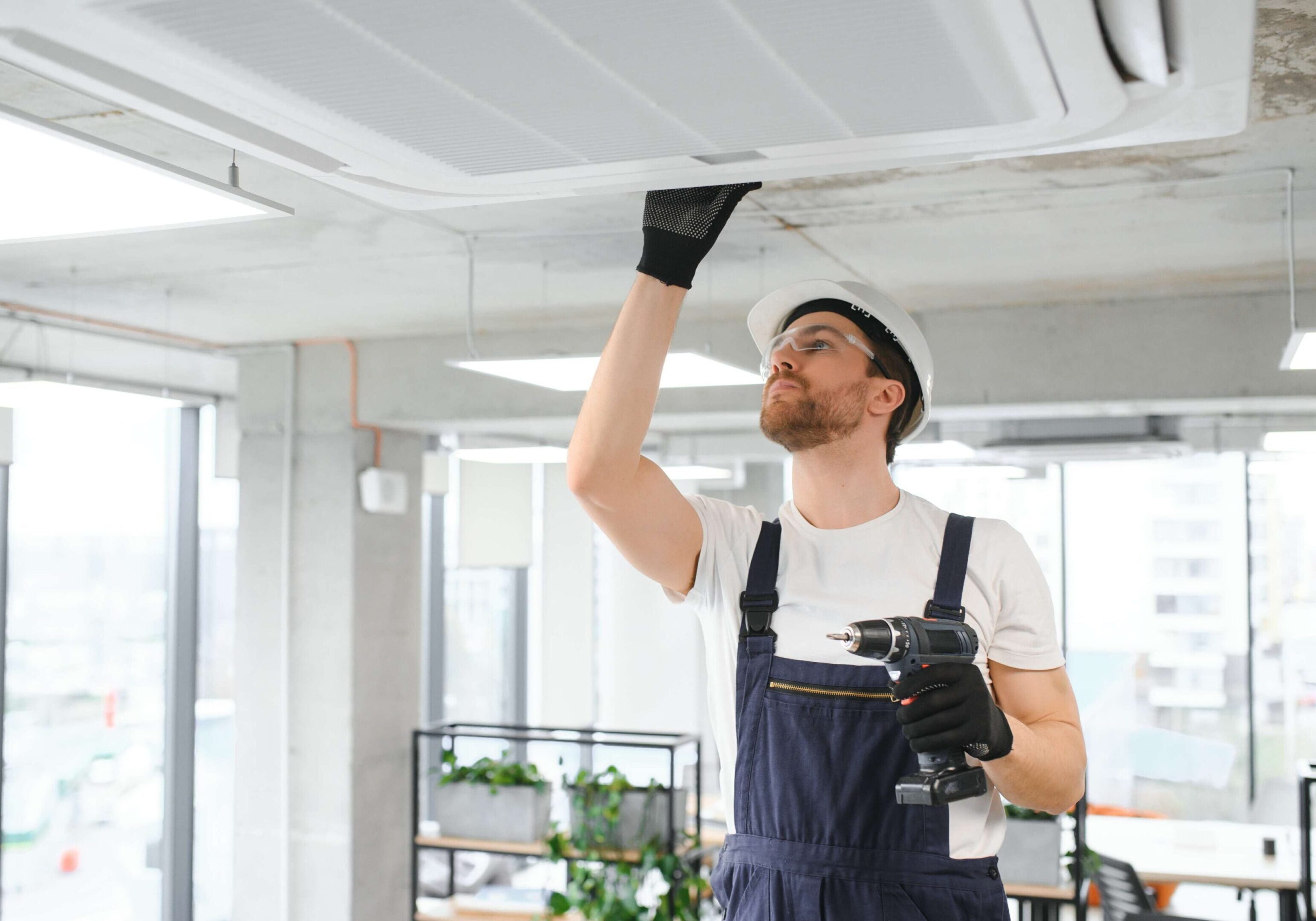 Technician inspecting ceiling air conditioning unit.